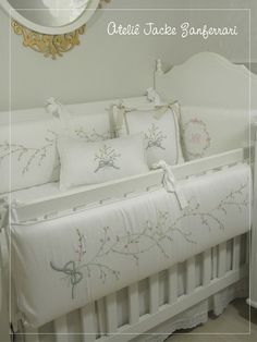 a white crib with pillows on top of it and a mirror above the crib