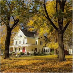 a large white house surrounded by trees in the fall