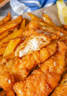 fried chicken and french fries on a plate with lemon wedges next to it, ready to be eaten