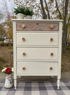 an old dresser has been painted white and is sitting on a checkered tablecloth