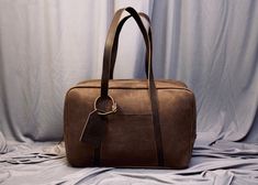 "Elevate your travel style with our exquisite Handcrafted Leather Travel Overnight Bag a fusion of elegance, durability, and wanderlust. This leather bag has a unique style of long handles that make this bag more stylish and easy to carry. LEATHER COLOUR: DARKEST BROWN CRUNCH Size: 18\"x12\"x6\"(LxHxW) FREE Personalization on the Leather tag. Key Features: Our artisans handcraft each travel bag with precision and care, resulting in a masterpiece that stands the test of time. Every stitch is a te Brown Rectangular Travel Bag, Modern Brown Rectangular Travel Bag, Rectangular Travel Bag With Leather Handles For Business Trips, Leather Handle Rectangular Travel Bag For Business Trips, Brown Rectangular Business Duffle Bag, Rectangular Brown Business Duffle Bag, Luxury Weekender Bag For Overnight Trips, Brown Rectangular Travel Bag With Leather Handles, Rectangular Leather Duffle Bag