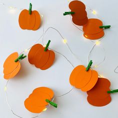 paper pumpkins and string lights on a white surface with orange tags attached to them