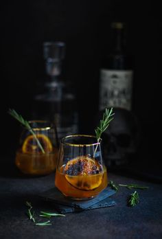 two glasses filled with liquid and garnished with rosemary