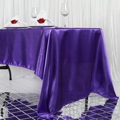 the table is set with two wine glasses and a purple cloth draped over it,