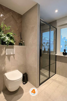 a bathroom with a toilet, shower and plants in the window sill on the wall