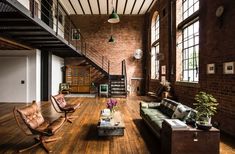 a living room filled with furniture and lots of windows next to a stair case on the wall