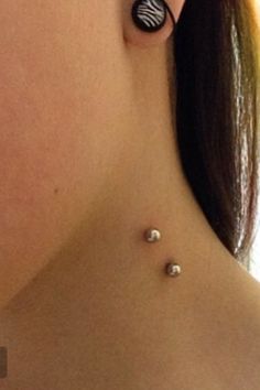 a close up of a woman's neck with earrings on her left side and an animal print design on the other side