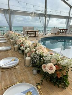 a long table with flowers and candles near the pool