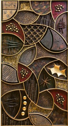 an art piece made out of metal and wood with different designs on the surface, including leaves