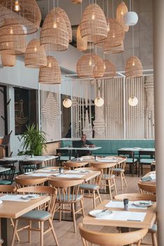 an empty restaurant with wooden tables, chairs and hanging lights above the dining room table