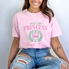 Elevate your golf attire with the charming "Golf Cart Princess Social Club" tshirt. Designed with the stylish golf enthusiast in mind, this Comfort Colors shirt is the perfect gift for the golf wife or golf girl in your life. Featuring an elegant and playful design, this apparel exudes both comfort and sophistication, making it suitable for a day on the course or a casual outing at the country club. This is a standard unisex size Comfort Colors Tee. For an oversized tee, please size up. If you a Cute Golf Shirts Women, Preppy Cotton Tops For Golf, Pink Short Sleeve Tops For Golf, Graphic Tee Tops For Golf, Graphic Tee Golf Tops With Short Sleeves, Graphic Tee Tops For Golf With Short Sleeves, Golf Wife, Golf Girl, Club Tshirt