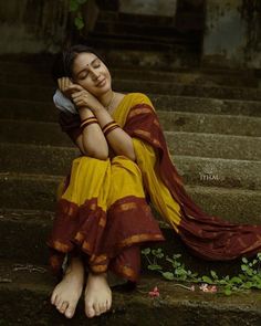 a woman is sitting on the steps with her head in her hands and eyes closed