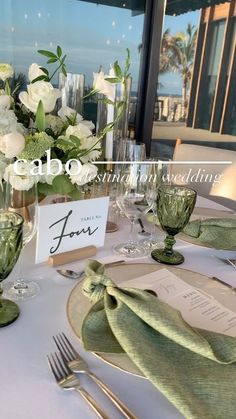 the table is set with white flowers and green napkins for an elegant wedding reception