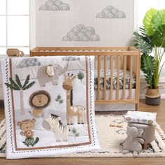 a baby crib bedding set with animals and trees on it, next to a potted plant