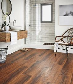 a bathroom with wood flooring and white tile on the walls, along with a wooden chair