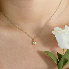 a close up of a person wearing a necklace with a flower in the foreground