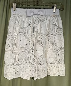 This is a cute vintage skirt cover or overlay, from the 60s or so. No brand label but tagged a size 7.  Waist measures 25", please see measurements.  Made of cotton lace in an open floral pattern with a solid white linen waist band & bow accent. This is a not a skirt, as it is open in back, but made to cover and accent a dress or skirt. Closes in the back with 3 hidden metal hooks & string loops.  The skirt is in very good condition. No soil or stains.  No holes or tears. Sweet! Measurements were taken with the garment lying flat. If you have never worn vintage before, please measure yourself!! Will fit best if your measurements are a little smaller than the measurements given. If you have any questions about measuring, please ask before purchasing. Waist measured from side seam to side se Vintage Style Skort For Summer, Vintage Skort For Summer, Vintage Lined Skort For Summer, Vintage Pencil Skirt For Spring, Vintage Summer Party Mini Skirt, Vintage Summer Lined Skort, Vintage White Skirted Bottoms, Vintage White Pleated Skirt, Vintage White Lined Skirt