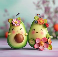 two green figurines with flowers on their heads, one has an avocado and the other has a flower in it's mouth