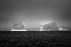 two icebergs floating in the ocean on a cloudy day