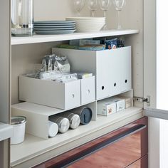 an open cabinet with wine glasses and plates on it