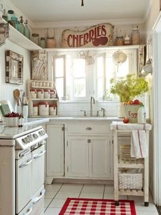 a white kitchen with red and white checkered rugs on the floor in front of an oven