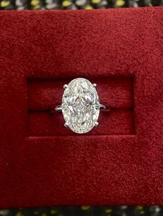 an oval cut diamond ring in a red velvet box