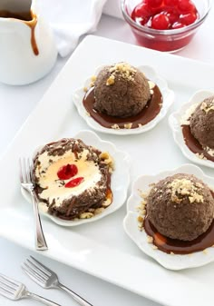 four desserts on plates with chocolate sauce and cherries in the center, ready to be eaten