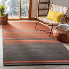 a living room with a chair, rug and window in the background that is open