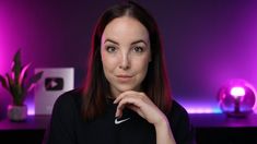 a woman with red hair is posing for a photo in front of purple lights and a plant