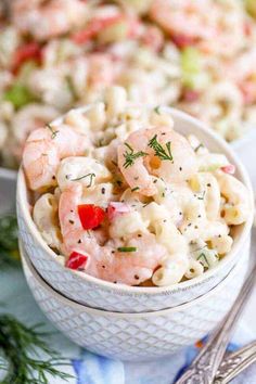 shrimp pasta salad in a white bowl on a blue and white place mat with silverware