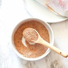 a bowl filled with spices next to a wooden spoon