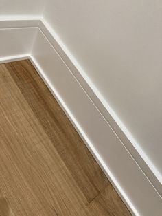 the corner of a room with white walls and wood flooring is shown in this image