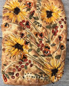 a pizza with sunflowers and cherries on it sitting on top of a wooden table