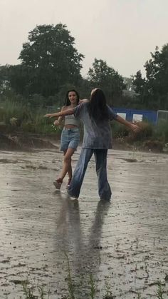 two people are playing in the rain with an umbrella