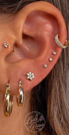 a woman wearing three different types of ear piercings