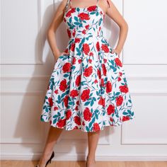 Della Floral Swing Dress, With A Stand Out Floral Print Of Bright Roses And Dark Petals On A Fresh White Base. With A Gorgeous Sweetheart Neckline Framed By Tie Shoulder Straps, This Style Is A Summer Stand Out Piece. The Fitted Bodice Which Leads Into A Swinging Skirt Is Reminiscent Of The 1950s Which We Hold Dear In Our Hearts. We Of Course Added Our Favourite Hidden Side Pockets To Add That Extra Ease To Your Day. Made Using A Comfortable And Stretchy Cotton, This Style Is Perfect For Going A White Floral Dress With Rose Print For Garden Party, Cotton Rose Print Dress For Garden Party, Bright Roses, Hearts And Roses, London Dresses, The 1950s, Fitted Bodice, Swing Dress, Hot Summer