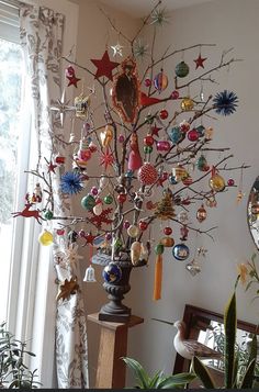 a christmas tree with ornaments hanging from it's branches in front of a window