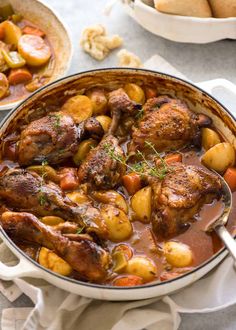 chicken stew with potatoes and carrots in a white pot on a table next to other dishes