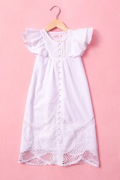 Introducing the Baby Jane Gown - a darling addition to your little one's wardrobe for special occasions! Crafted from soft white cotton, this gown features a charming round neckline with delicate pleated detailing and sweet short ruffle sleeves. The maxi-length skirt is adorned with intricate embroidered/crochet detailing, adding a touch of elegance to the button-up style. Ensure your baby girl looks adorable and feels comfortable in the timeless elegance of the Baby Jane Gown. Feminine Cotton Flutter Sleeve Dress, Feminine Flutter Sleeve Cotton Dress, Spring Baptism Dress With Broderie Anglaise, White Ruffled Nightgown For Sleepover, Spring Broderie Anglaise Baptism Dress, Cotton Dresses With Lace Trim And Ruffle Sleeve, White Feminine Ruffle Sleeve Dress, Cotton Dress With Lace Trim And Ruffle Sleeves, Feminine White Ruffle Sleeve Dress