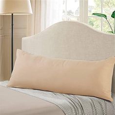 a bed with a white headboard and beige pillows