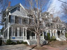 a large house with many windows and white trim on the side of it's front porch