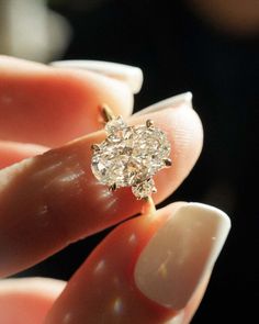 a woman's hand holding a ring with a large diamond on the middle of it