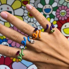 a person's hand with four rings on it and the word joy written in different colors