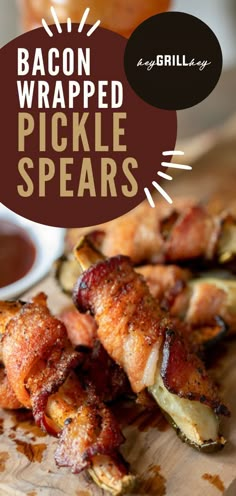 bacon wrapped pickle spears on a wooden cutting board with dipping sauce in the background