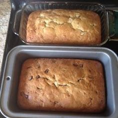 two loafs of bread sitting in pans on top of a counter