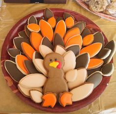 a decorated turkey on a plate with cookies in the shape of leaves and an orange tail