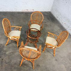 a set of rattan and wicker dining chairs with glass table on concrete floor