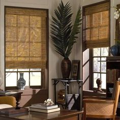 a living room filled with furniture and windows covered in bamboo blind shades on top of them