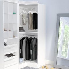 a white closet with clothes and shoes on the floor in front of a large mirror