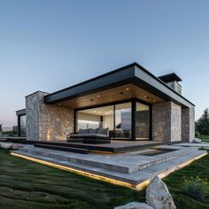 an outdoor living area with stone walls and steps leading up to the front door is lit by recessed lights